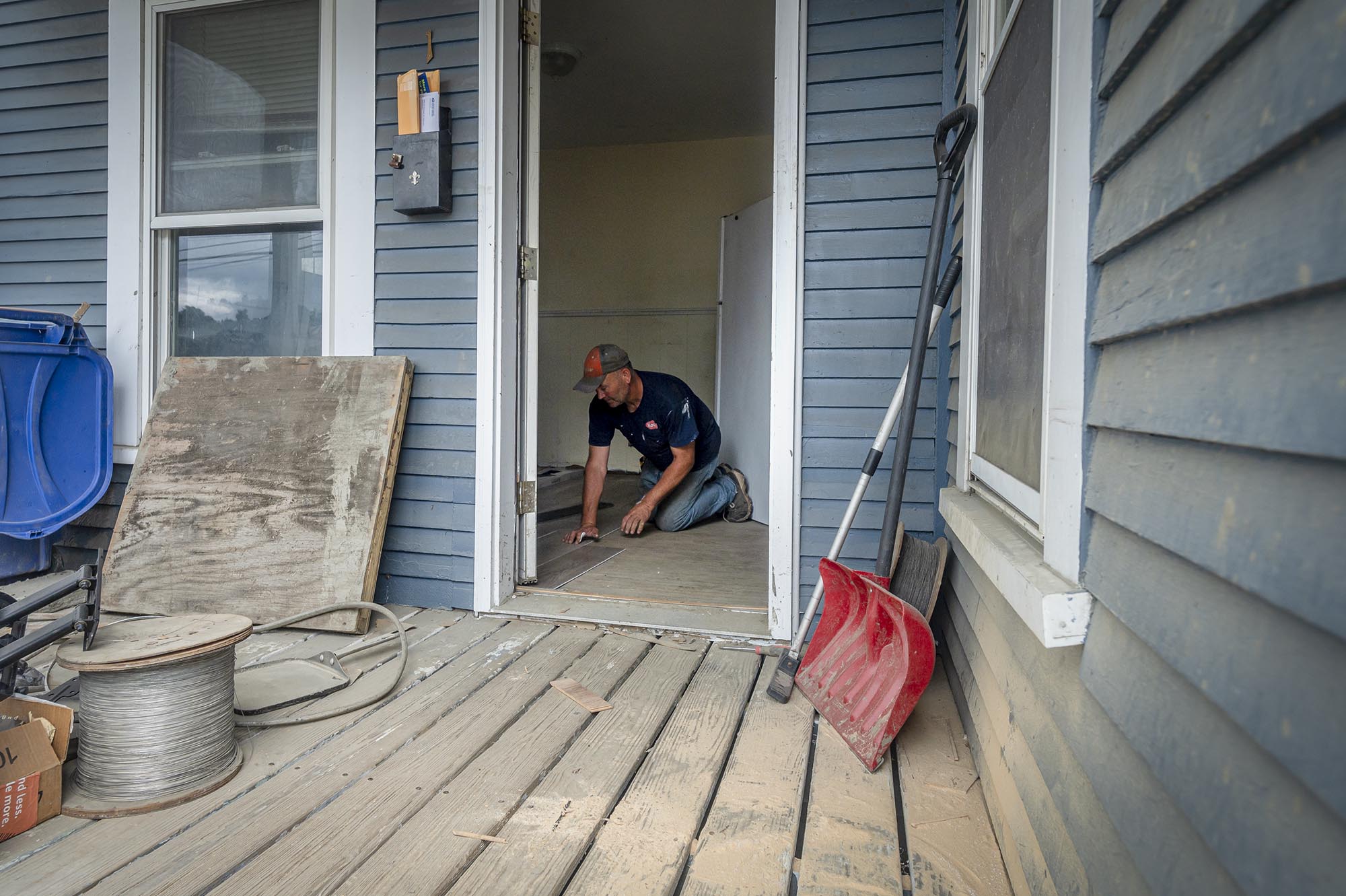 A man standing on a porch with a shovel.