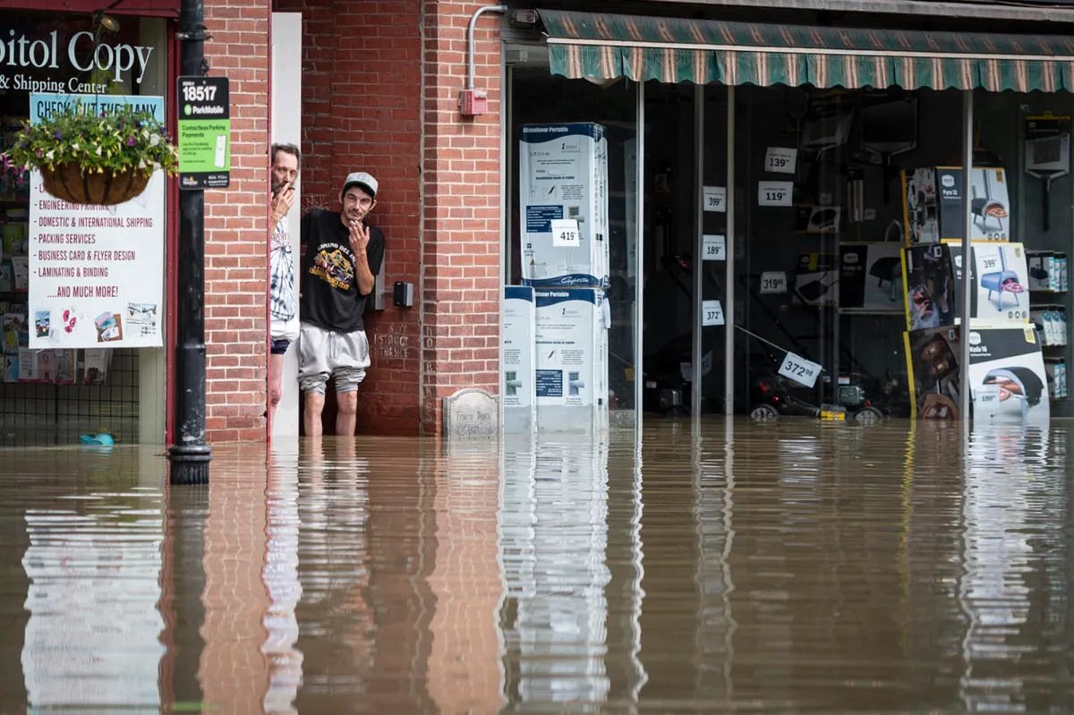 a man is standing in a flooded street near a store.