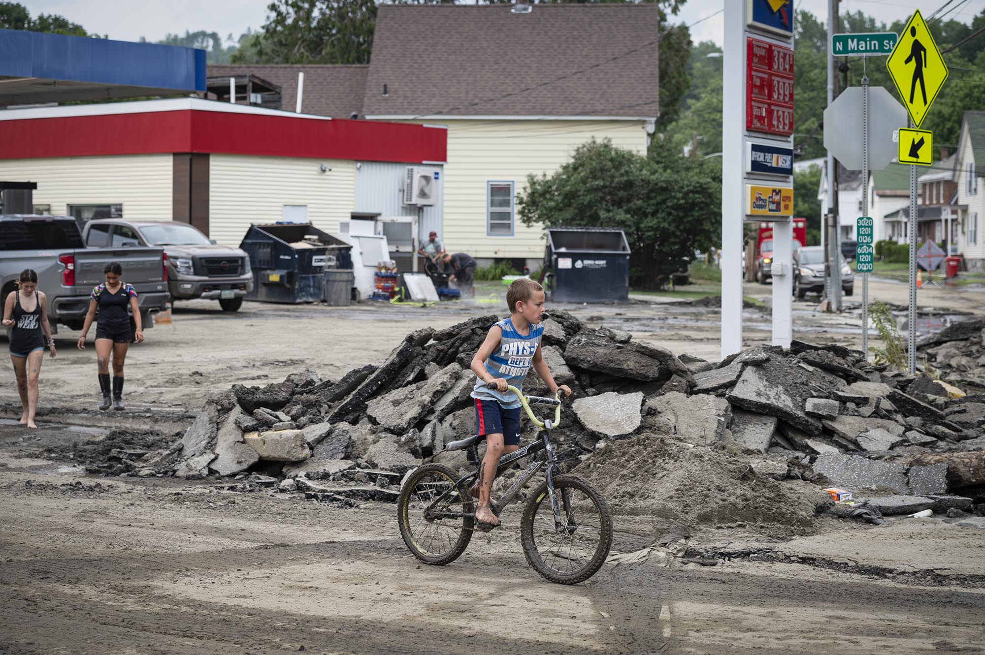 a boy riding a bike in front of a pile of rubble.