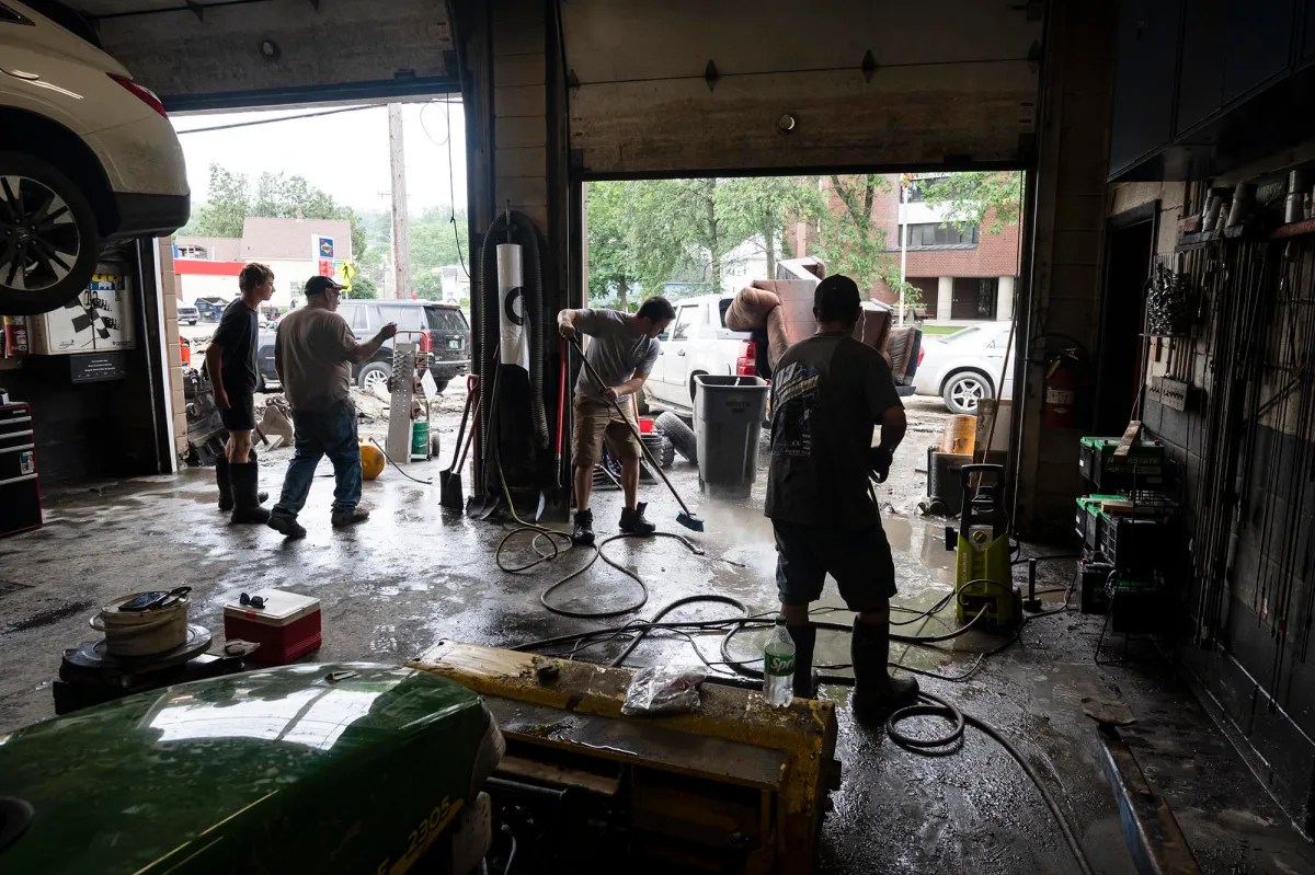 a group of people working on a car in a garage.
