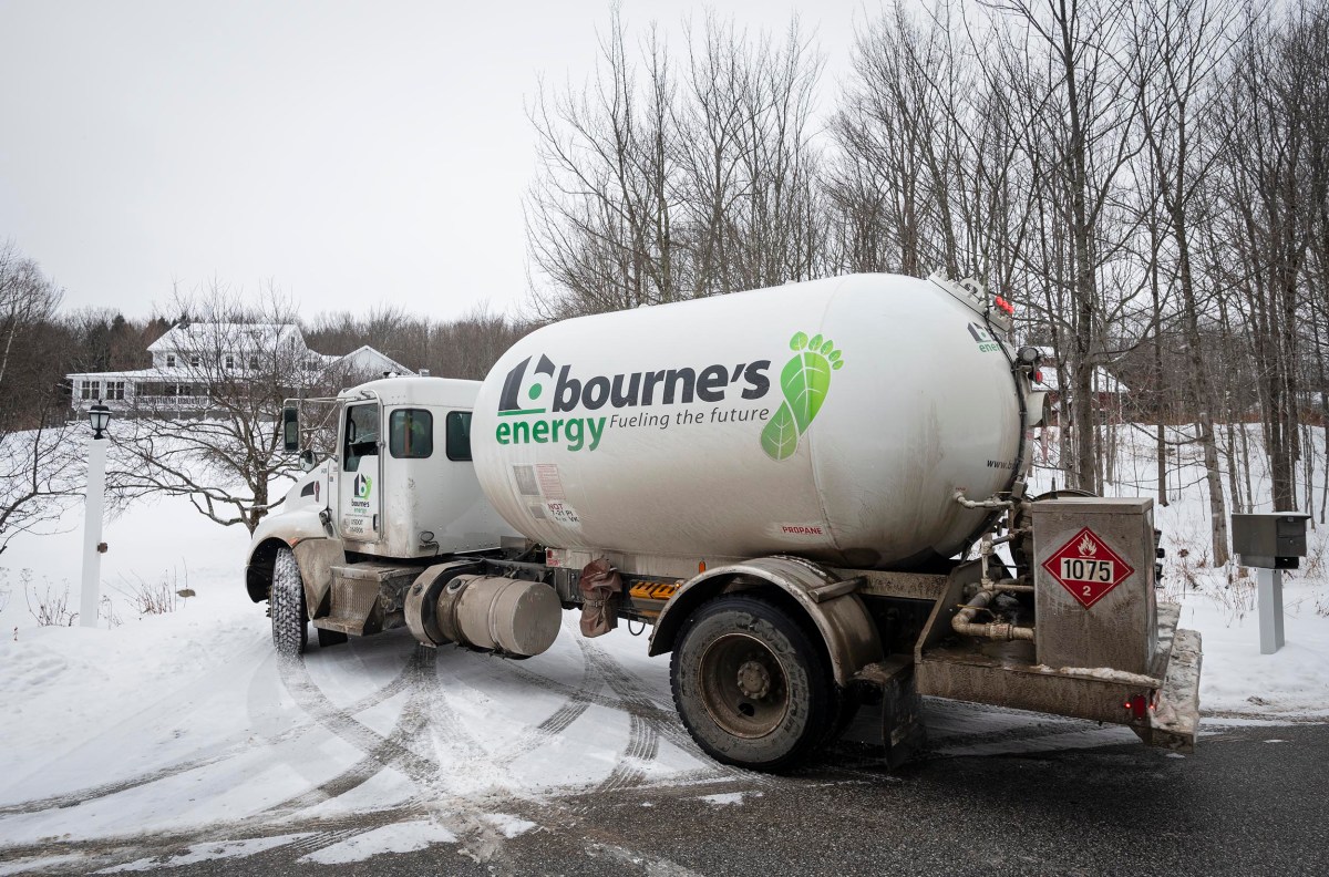 A Bourne's Energy truck parked on a snowy road near bare trees and a house in the background.