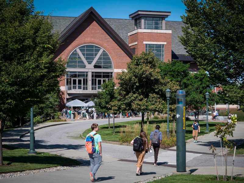 A group of people walking down a sidewalk in front of a building.