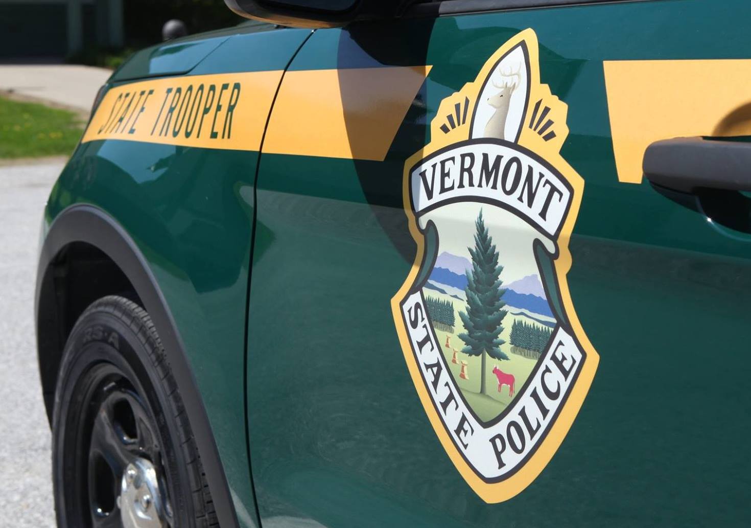Close-up of a Vermont State Police vehicle, showing the state's emblem and the words "State Trooper" on the side.