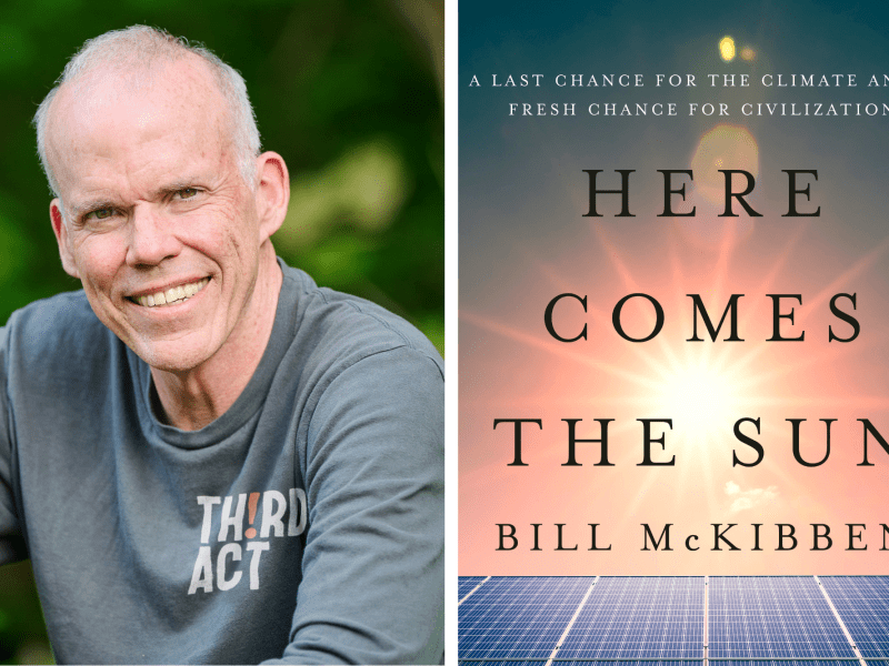A man smiles outdoors next to the cover of a book titled "Here Comes The Sun" by Bill McKibben, featuring a solar panel and sky background.