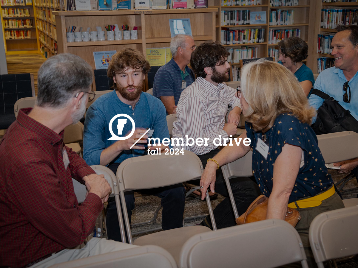 People sitting and conversing in a library setting during a member drive event. "Member Drive Fall 2024" text overlay is present in the center of the image. Bookshelves are visible in the background.